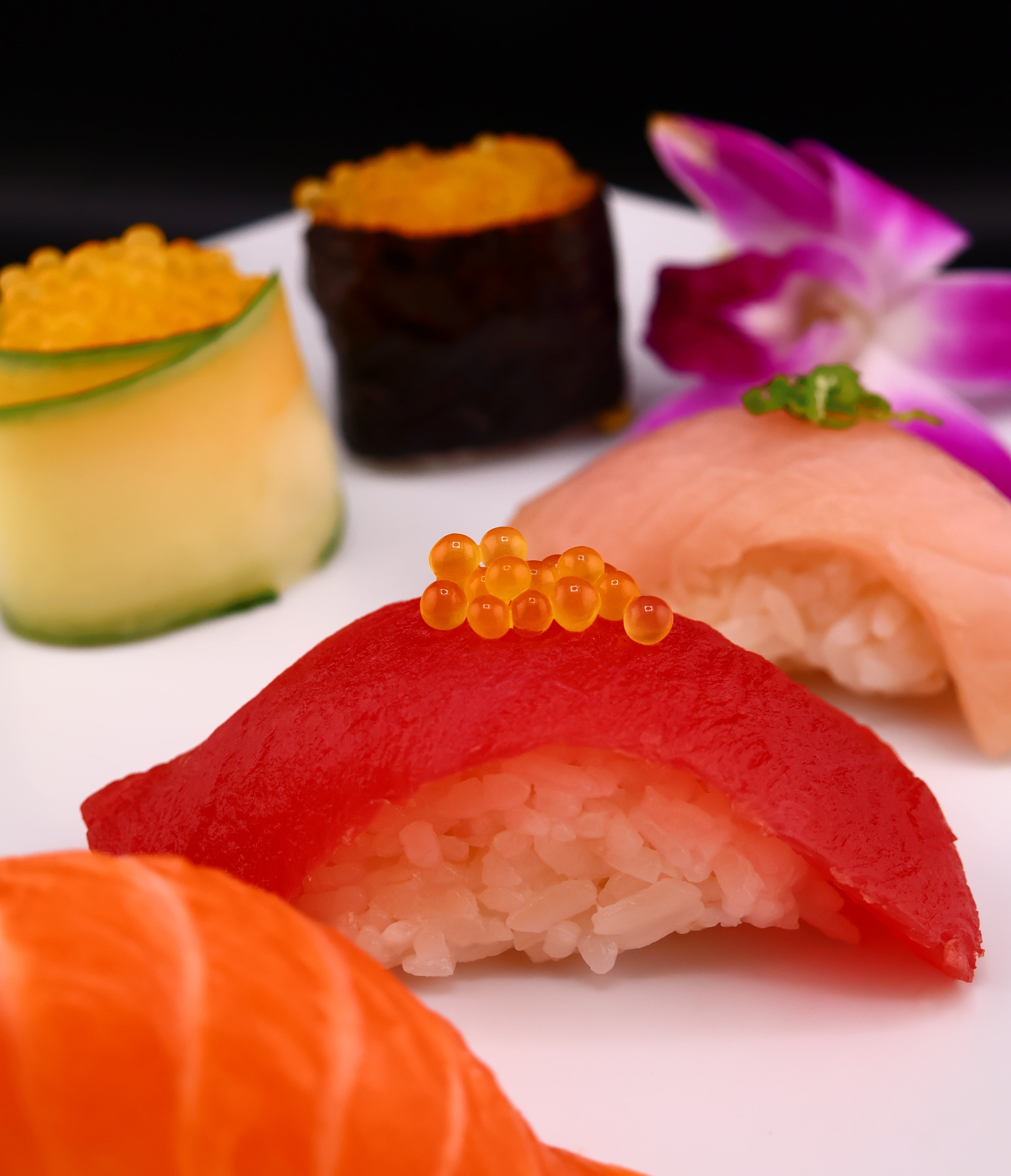 Assorted sushi pieces on a white plate with a blurred background